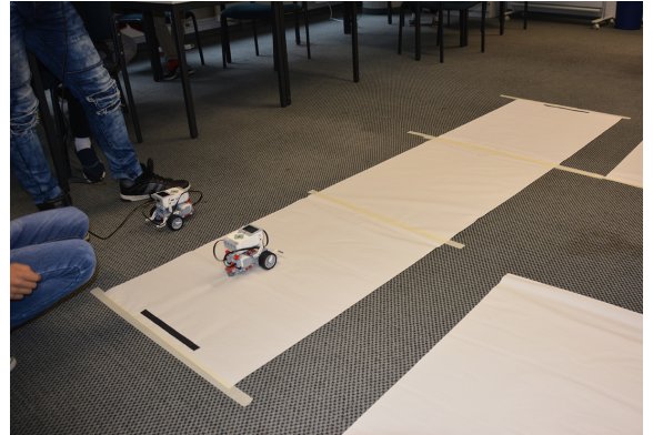 Lego Roboter fährt über eine Papierbahn am Boden
