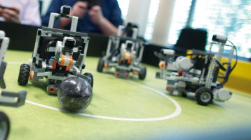 3 Legoroboter spielen auf einem Fussballtisch Fussball (Bild: Manfred Stern, FH Köln)