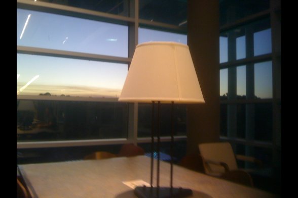 Stehlampe auf einem Tisch - hinter dem Fenster geht die Sonne unter