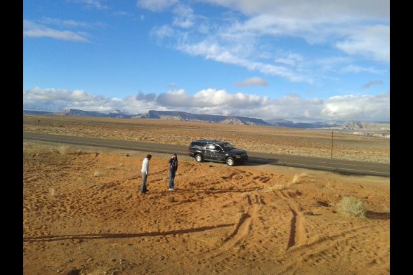 Blick auf Auto und zwei Menschen und eine einsame Straße in der Wüste