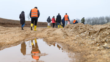 Personen mti Gummistiefeln auf einem Feld Personen mti Gummistiefeln auf einem Feld