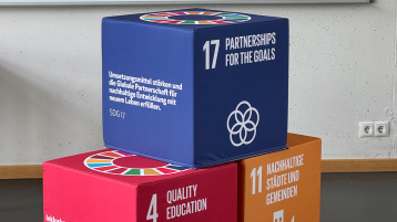 Drei Würfel mit den Sustainable Development Goals