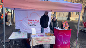 Zwei Personen an einem Stand unter einem Pavillon