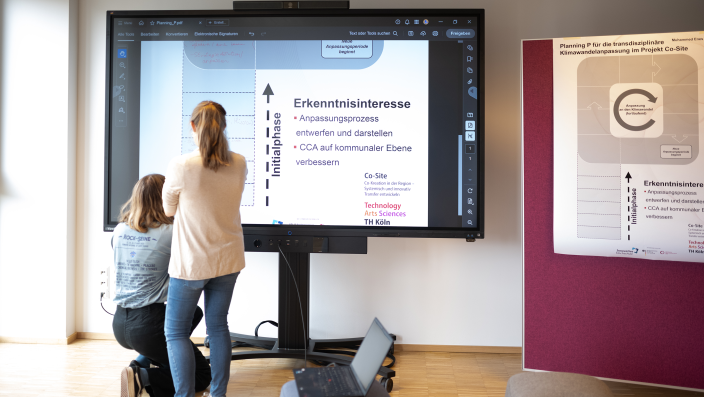 Zwei Personen vor einem großen Bildschirm