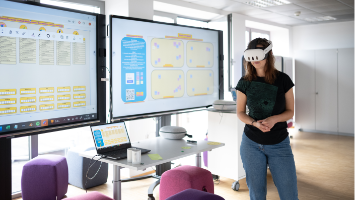 Eine Frau mit einer VR-Brille vor einem Bildschirm