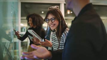 Junge Menschen stehen vor einer Tafel, eine Person lacht in die Kamera (Bild: AdobeStock)