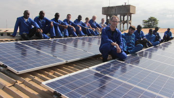 Das deutsch-ghanaische Photovoltaik-Team in Blaumännern vor der Solaranlage. (Bild: Thorsten Schneiders)