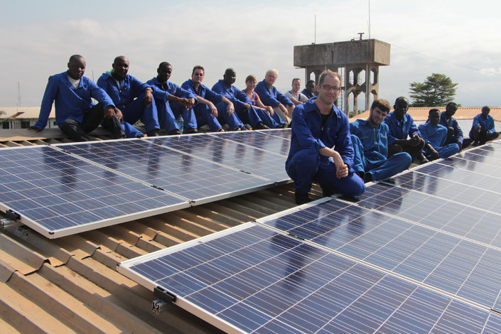 Das deutsch-ghanaische Photovoltaik-Team in Blaumännern vor der Solaranlage.
