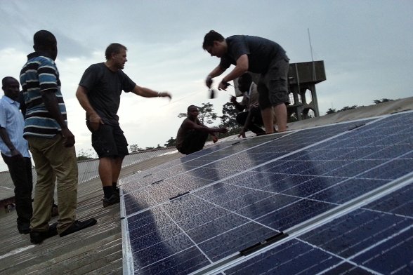 Mehrere Personen installieren Solarzellen auf einem Dach.