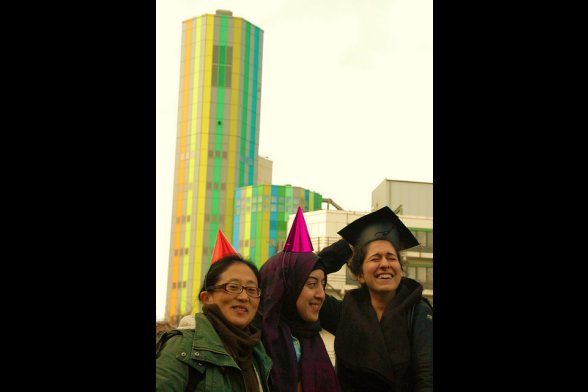 Drei Studentinnen unterschiedlicher Herkunft mit Party- und Doktorhütchen auf dem Kopf