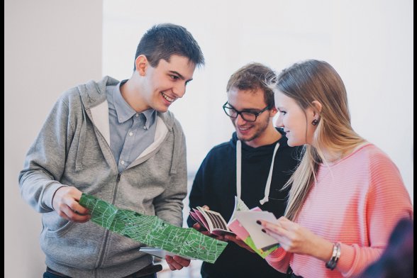 Drei Studierende betrachten einen Stadtplan.