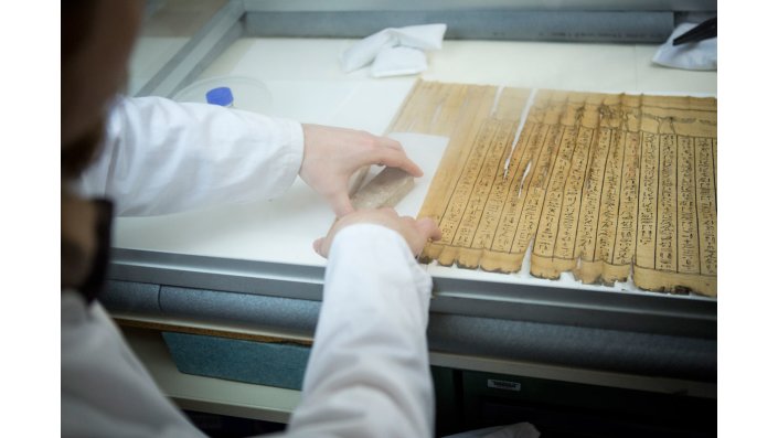 Das Papyrus wurde in einem Plexiglaskasten bei 96 Prozent Luftfeuchtigkeit ausgerollt. Die hohe Luftfeuchtigkeit löst verklebte Stellen auf und macht das Papyrus geschmeidiger. 