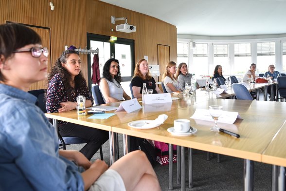 Neun Frauen sitzen an einem langen Tisch