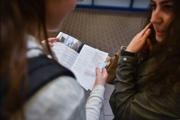 Zwei Studieninteressierte mit einer Broschüre