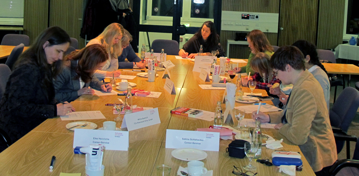 Frauen sitzen um einen Tisch mit Arbeitsmaterialien