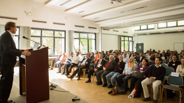 Ein Redner am Pult spricht zu einem Publikum. (Bild: Heike Fischer/TH Köln)