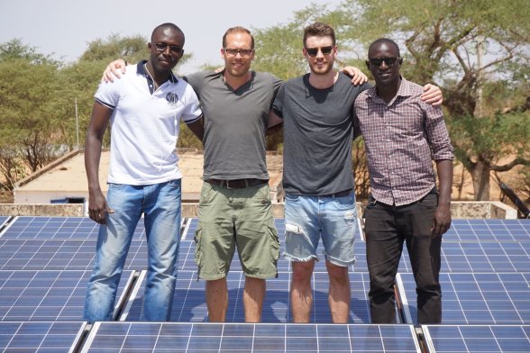 Vier Personen stehen hinter einer Photovoltaikanlage