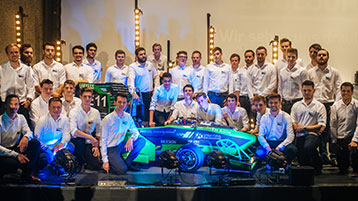 Gruppenfoto des Teams eMotorsport Cologne mit dem neuen Rennwagen. (Bild: Costa Belibasakis/TH Köln)