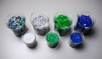 Bechergläser mit farblich sortierten PET-Recyclingrohstoffen und Granulat Bechergläser mit farblich sortierten PET-Recyclingrohstoffen und Granulat