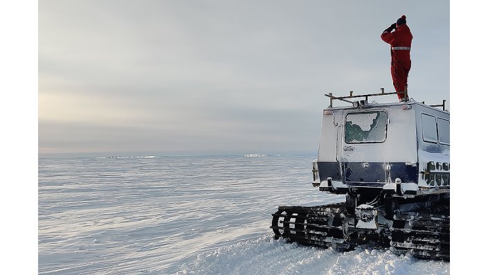 Ein Forscher steht auf einem Fahrzeug und erkundet Eisberge