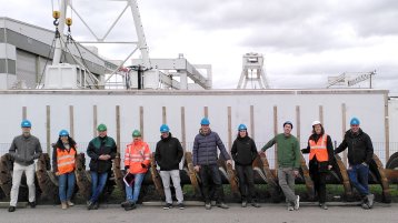 Gruppenbild des internationalen Forschungsteams vor einem Bohrkopf (Bild: TH Köln)