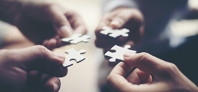 Vier Hände fügen vier Puzzelteile zusammen. (Bild:AdobeStock/Johnstocker)
