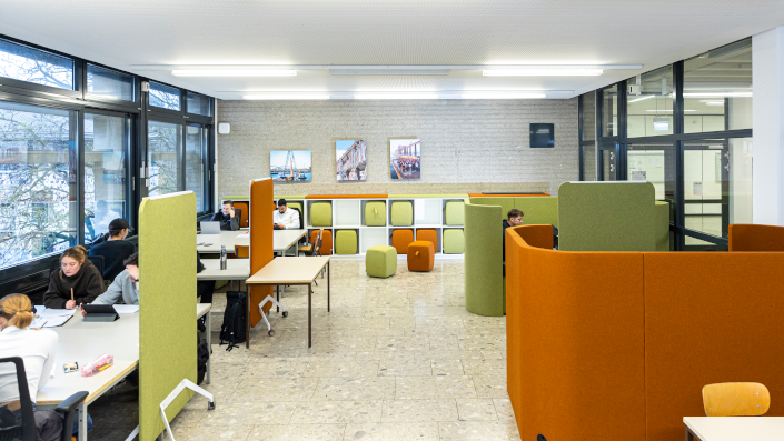 Umgestalteter Arbeitsraum mit Loungemöbeln für Gespräche in Kleingruppen, sowie mobilen Stellwänden, Hockern und bequemen Bürostühlen. 