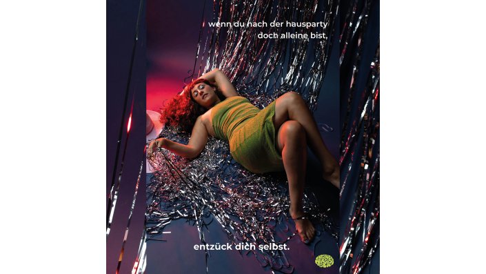 Werbekampagne zu den Sextoys. Eine Frau liegt in einem grünen Kleid auf dem Boden. 