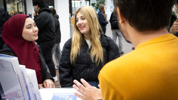 Zwei Studentinnen informieren sich am Infostand im Foyer am Campus Deutz (Bild: Heike Fischer/TH Köln)