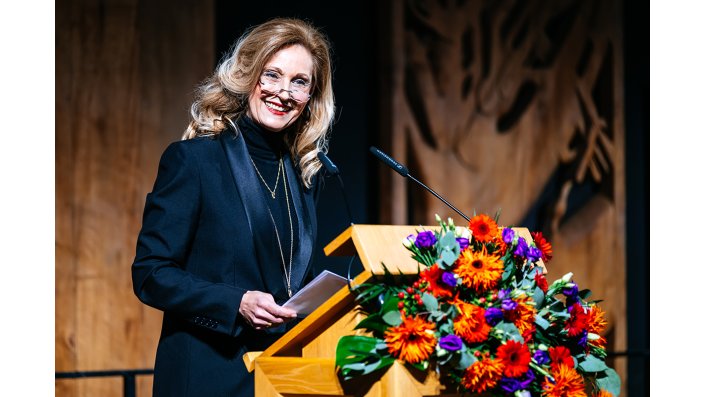 Ulrike Lubek steht an einem Rednerpult und spricht zum Publikum.