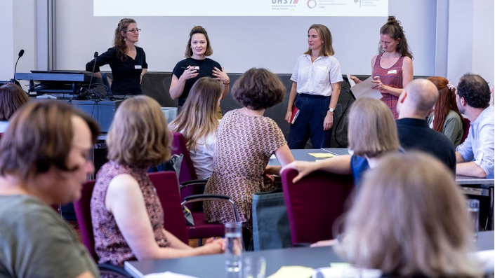 vier Frauen präsentieren vor einem Plenum