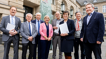 Die acht Verantwortlichen der TH Köln und der beteiligten Stiftungen bei der Vertragsunterzeichnung stehen vor dem Hauptgebäude der TH Köln an der Claudiusstraße (Bild: Michael Bause/TH Köln)