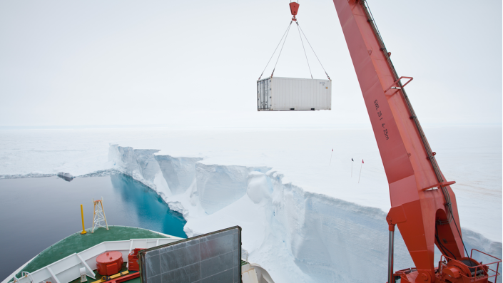Kran, der im Schnee Container auf ein Schiff setzt
