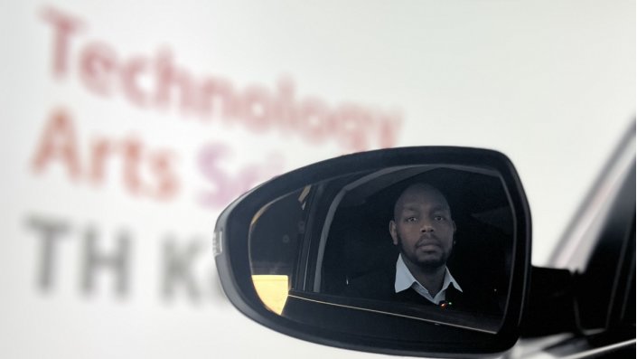 Spiegelung von Prof. Dr. Kamau im Seitenspiegel eines Autos