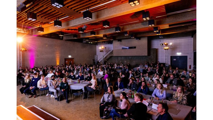 Fast alle Teilnehmenden des Meet and Greets. Sie sitzen an Tischen in einem großen Saal. 