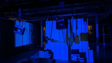 Aufgestellte Laptops, Musikinstrument hängen von der Decke, alles von blauem Licht angestrahlt (Bild: Rochus Aust)