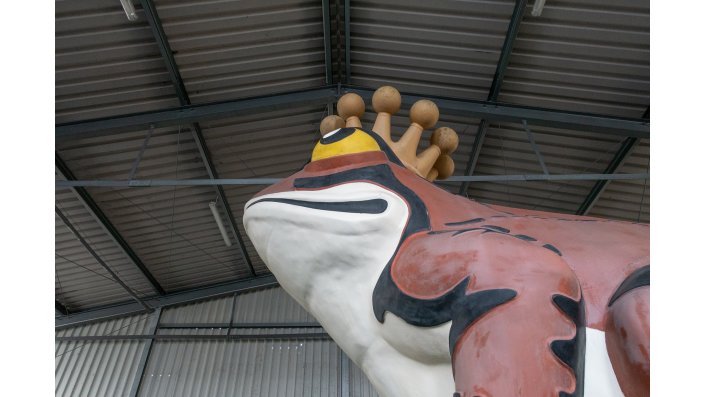 Nächste Station: Froschskulptur. Die über vier Meter hohe Werbefigur befindet sich zurzeit für die Konservierungs- und Restaurierungsmaßnahmen in einer Lagerhalle, in der die Dimensionen der Figur deutlich werden.