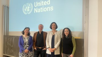 Vortragende Marlies Wulf sowie Professor*innen des ITMK stehen vor dem Beamerbild des Vortrags zum DÜD (Bild: Ralph Krüger, TH Köln)