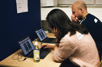 Ein Mann und eine Frau sitzen vor zwei Computer-Bildschirmen Ein Mann und eine Frau sitzen vor zwei Computer-Bildschirmen