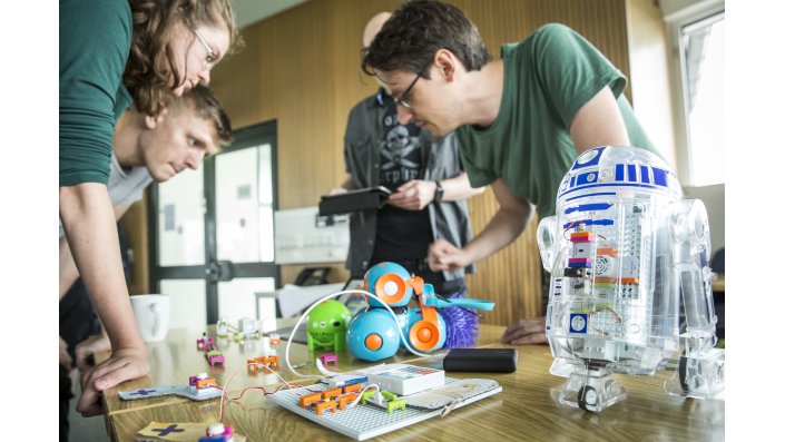 Ein Stand mit einigen kleinen Robotik-Entwicklungen, über den sich Gäste und Aussteller beugen