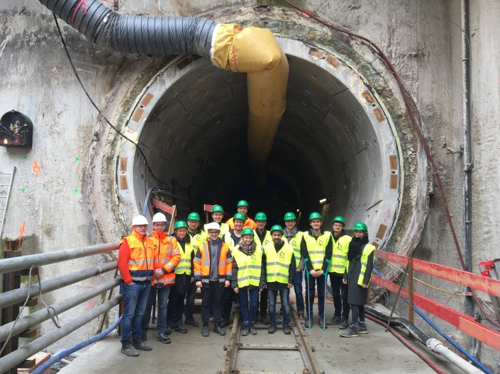 Eine Gruppe von Studierenden und Mitarbeitern steht vor dem Zugang zu einem U-Bahntunnel 