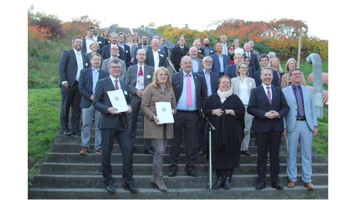 Die zahlreichen Teilnehmer*innen der Tagung nutzen das gute Wetter für ein Gruppenbild vor der Gipfeltreppe