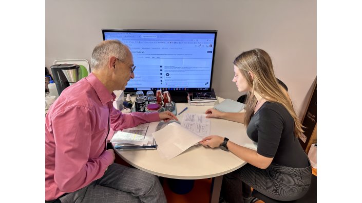 Prof. Dr. Dirk Burdinski und Magdalena Kroll sitzen am Tisch und schauen in Unterlagen.