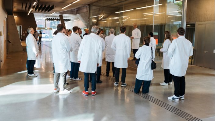 Prof. Dr. Dirk Burdinski steht mit einer Gruppe an Interessierten im Flur des Campus Leverkusen