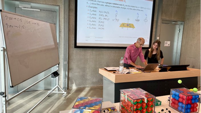 Prof. Dr. Dirk Burdinski und Magdalena Kroll stehen am Pult im Hörsaal und schauen auf das Tablet.