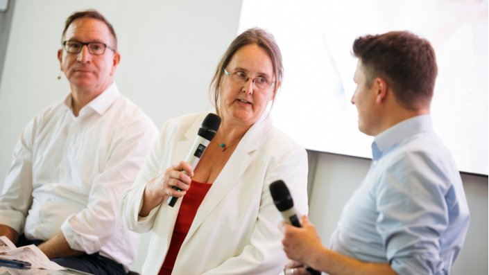 Prof. Dr. Birgit Glüsen spricht ins Mikrofon, neben ihr sitzen Christoph Kappenhagen und Daniel Wauben.