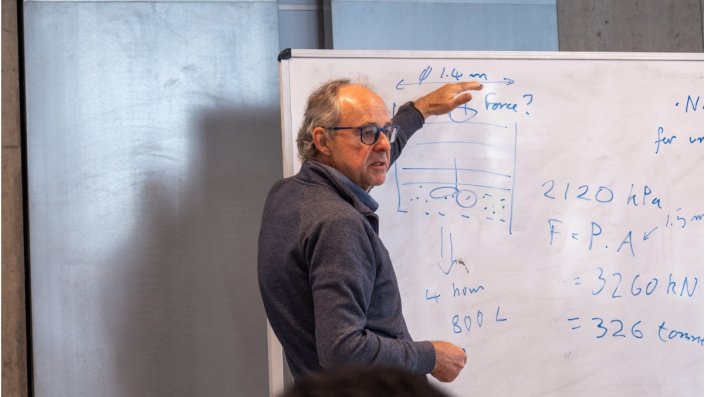 Philipp Davis steht an einem Board und erläutert ein Rechnung.