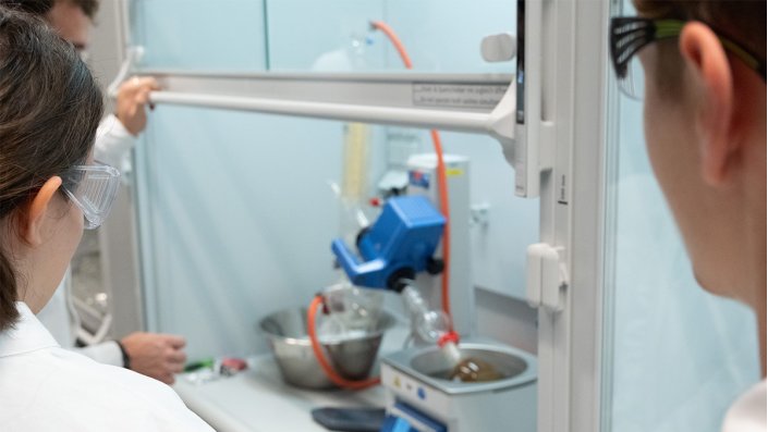 Zwei Schüler*innen stehen vor einem Abzug und beobachten einen Rotationsdampfer