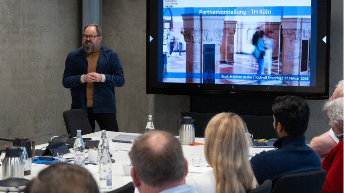 Prof. Dr. Stephan Barbe steht vor einem Beamer und schaut in die Runde.