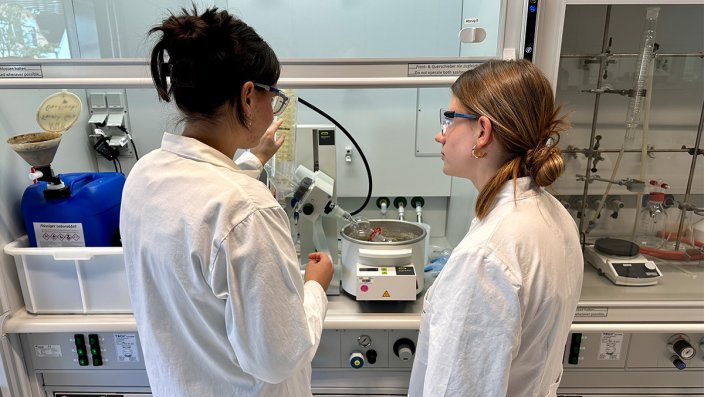 Zwei Frauen stehen im Labor vor einem Abzug.